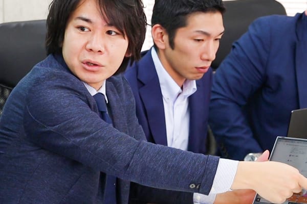 代表取締役と社員が、ノートパソコンを見ながら議論している様子です。