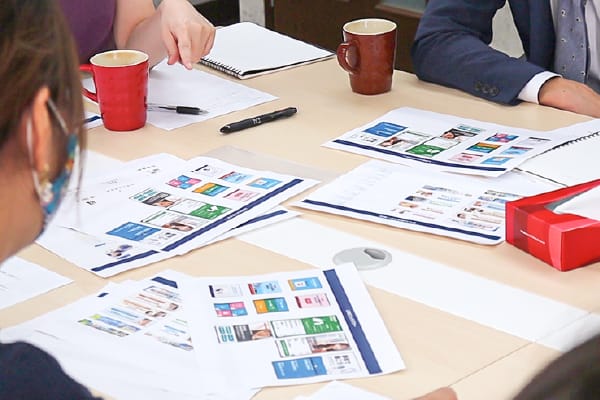 デスクの上に開かれたノートと複数の書類、カラフルなペンが置かれています。